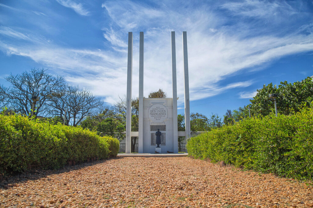 French War Memorial in Pondicherry with stone structure and tribute wreaths near the Promenade Beach.
