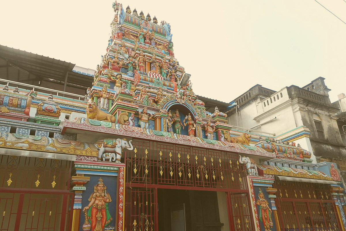 The colorful gopuram and entrance facade of the Kanniga Parameswari Temple in Pondicherry, showing traditional Hindu sculptures and architectural details.
