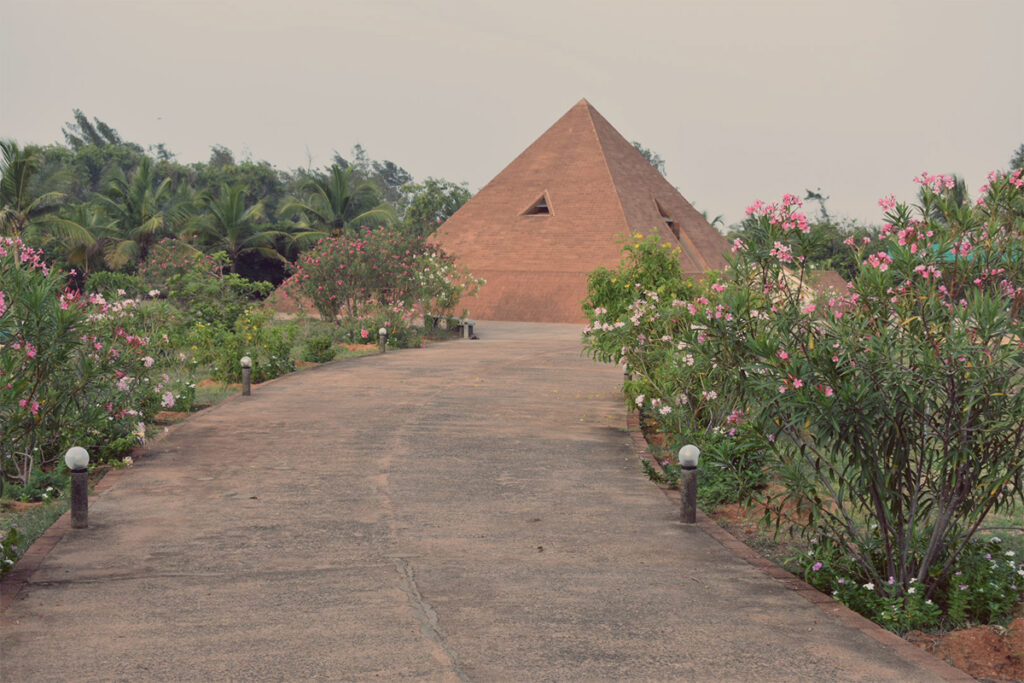 A photograph of the unique pyramid-shaped architecture of the Sri Karneshwar Nataraja Temple located near Pudukuppam Beach in Puducherry.