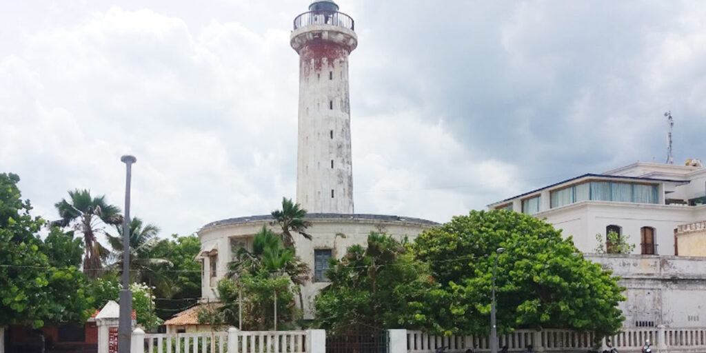 Old Lighthouse in Puducherry standing tall by the seashore during sunset, with visitors enjoying the scenic view of the Bay of Bengal