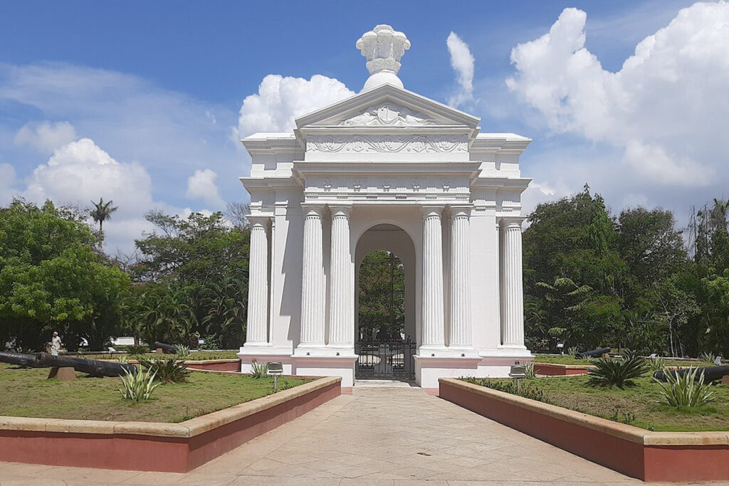 The majestic white Aayi Mandapam monument surrounded by lush green trees in the center of Bharathi Park, Pondicherry.