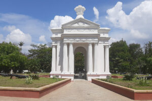 The majestic white Aayi Mandapam monument surrounded by lush green trees in the center of Bharathi Park, Pondicherry.